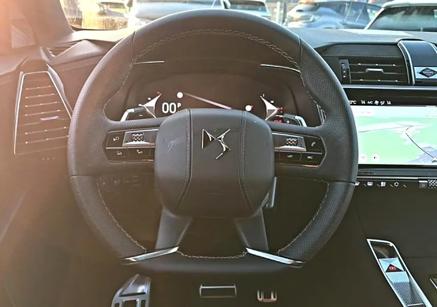 Vue rapprochée du volant noir en cuir du DS7 1.5 BlueHDi 130 avec tableau de bord digital et écran tactile GPS.