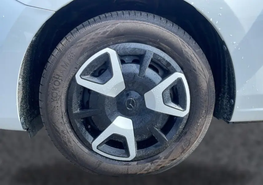 Gros plan sur la roue avant droite d’une Mazda2 blanche avec jante noire et inserts gris.