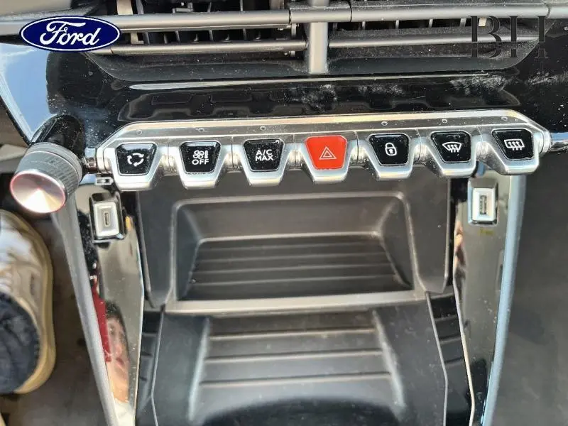 Vue rapprochée des commandes centrales avec boutons chromés et rouge sur fond noir brillant d'une Peugeot 208 Blanc Banquise.