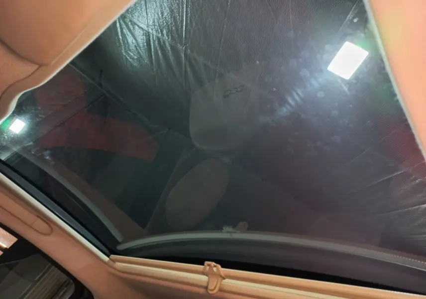 Toit panoramique en verre de la FIAT 500 noire, vue intérieure vers le ciel avec reflet du siège avant.