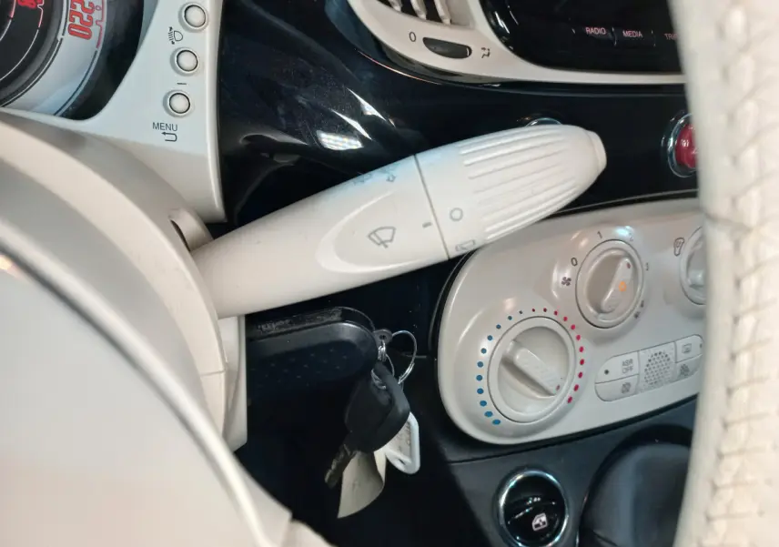 Détail intérieur côté gauche montrant la commande d’essuie-glace et les réglages de climatisation sur tableau de bord noir et beige.