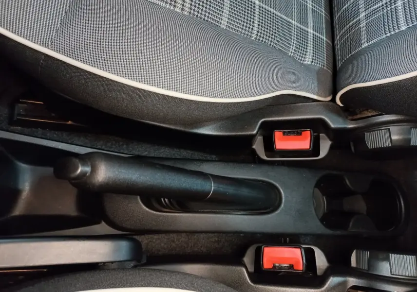 Vue rapprochée de la console centrale avec frein à main manuel et sièges tissu noir à motifs gris de la Fiat 500 Lounge 2018.