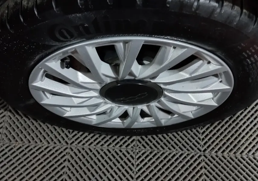 Gros plan sur la jante argentée d'une FIAT 500 noire, mettant en valeur le logo central et le pneu Continental.