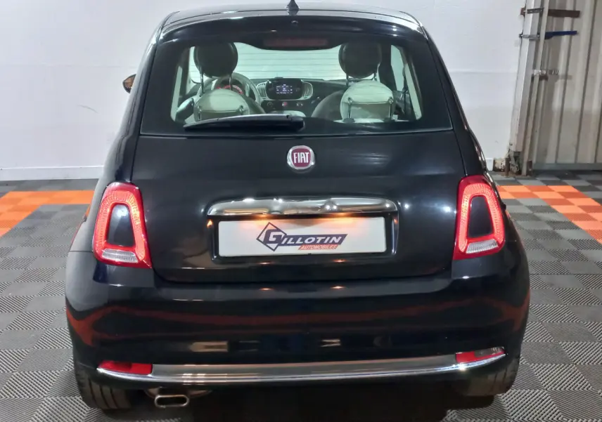 Vue arrière d'une FIAT 500 noire 2018 avec feux arrière allumés et plaque d'immatriculation encadrée chromée.