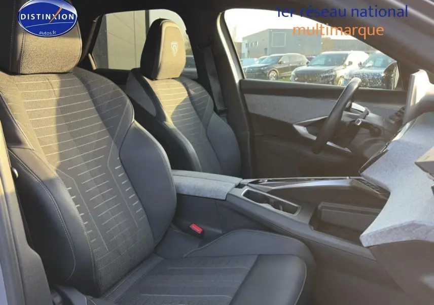 Intérieur avant droit du Peugeot 3008 gris 2025, sièges tissu et cuir avec accoudoir central et volant multifonction.