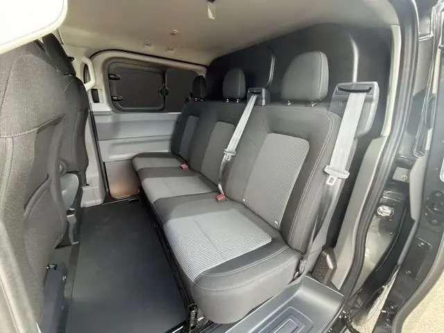 Vue intérieure côté droit du Volkswagen Transporter gris foncé 2026, montrant la banquette arrière trois places avec ceintures de sécurité.