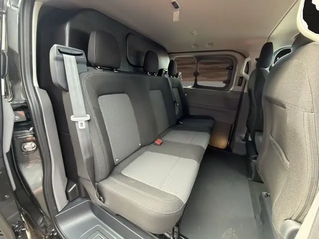 Vue intérieure côté droit du Volkswagen Transporter gris foncé, montrant la banquette arrière trois places et les sièges avant.