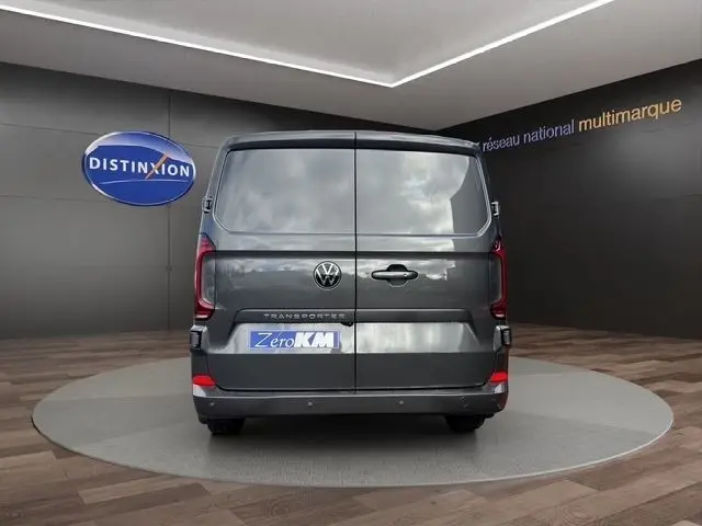 Vue arrière du Volkswagen Transporter gris foncé 2026, portes battantes fermées, logo et badge visibles, en showroom.