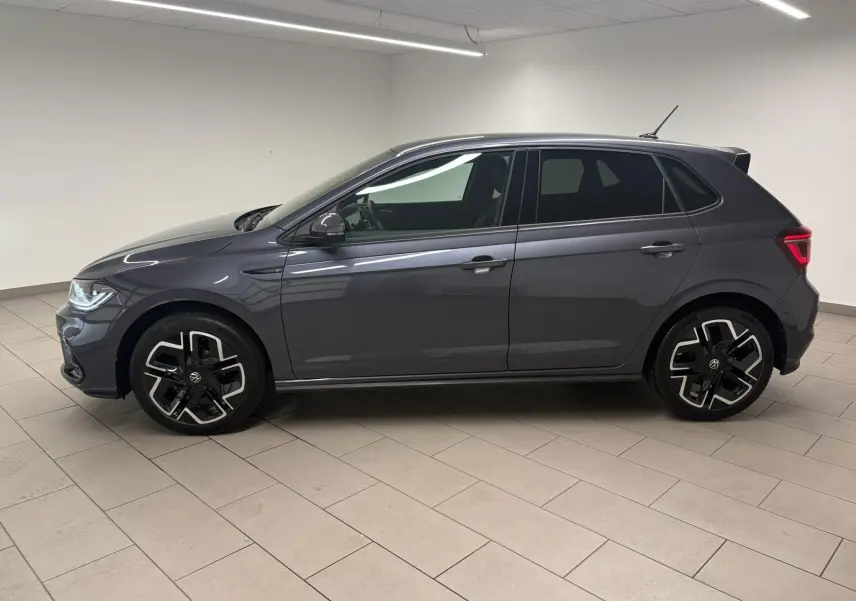Volkswagen Polo 1.0 TSI R-Line gris cendré vue de profil côté gauche avec jantes alliage distinctives en intérieur blanc.