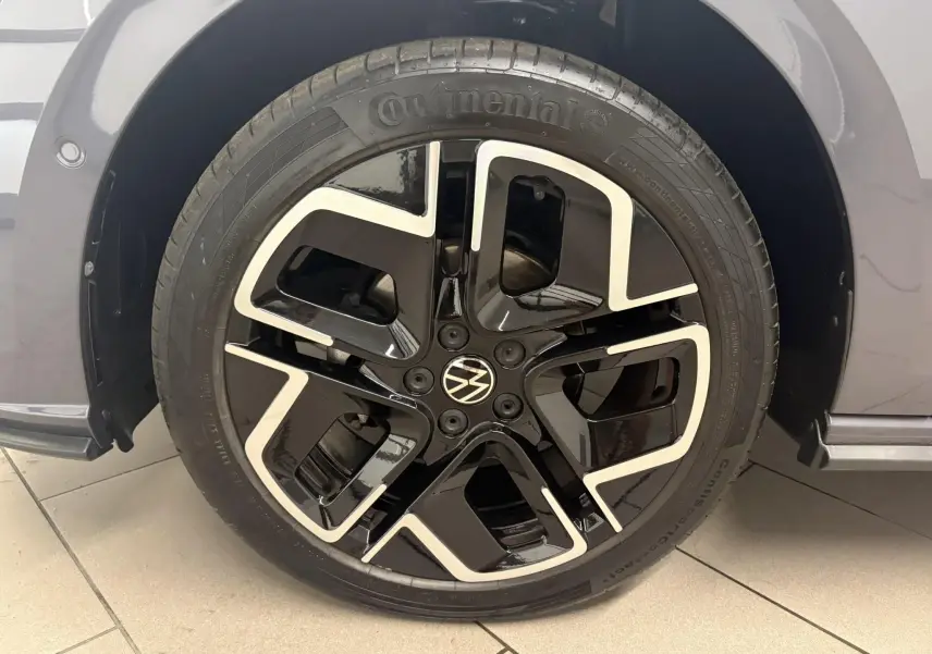 Gros plan sur la jante noire et argentée d'une Volkswagen Polo gris cendré, mettant en valeur le logo VW central.