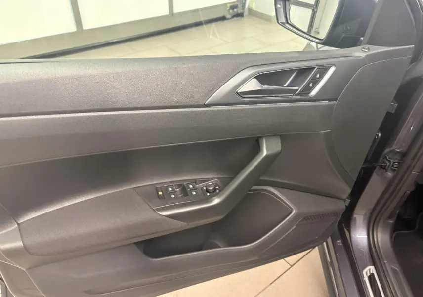 Vue rapprochée de la porte avant gauche intérieure d'une Volkswagen Polo gris cendré avec commandes de vitres et serrure.