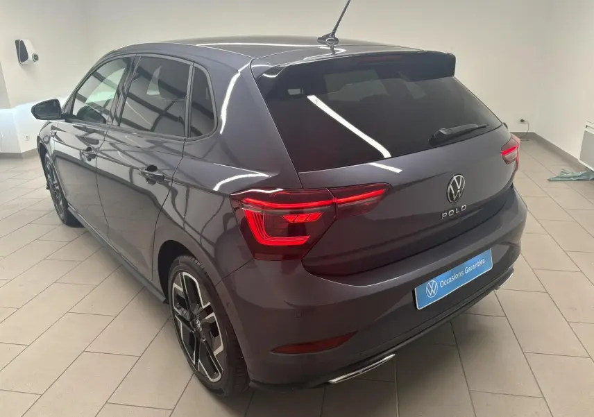 Volkswagen Polo 1.0 TSI R-Line gris cendré vue 3/4 arrière droit en intérieur avec feux LED et jantes noires.