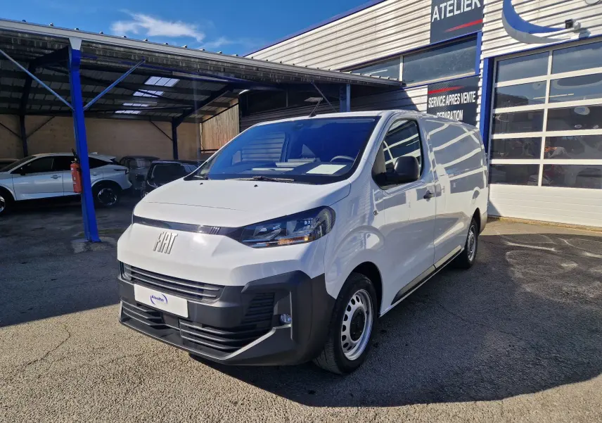 Fourgon FIAT Scudo blanc en 3/4 avant droit, avec pare-chocs noir et calandre moderne, stationné devant un atelier.