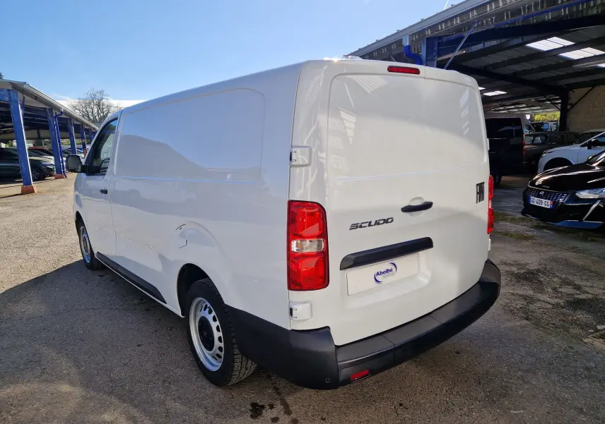Fiat Scudo Fourgon blanc vu en 3/4 arrière droit, avec hayon fermé et pare-chocs noir mat, stationné en extérieur.