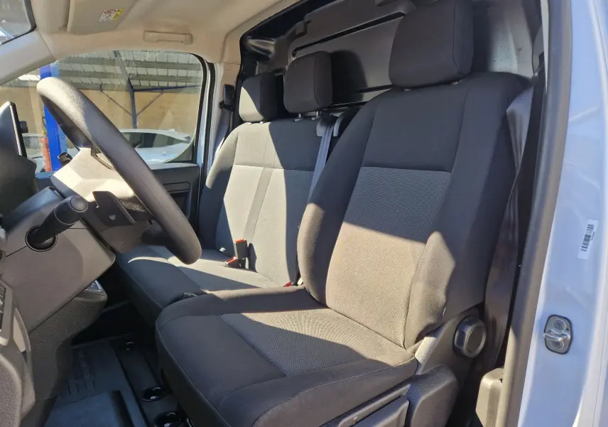 Vue intérieure côté conducteur du FIAT Scudo Fourgon blanc 2024, montrant les sièges en tissu gris et noir.