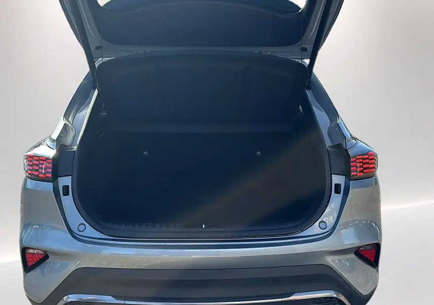 Vue arrière du coffre ouvert d'un KIA Xceed gris 2024 avec feux arrière LED allumés et pare-chocs chromé.