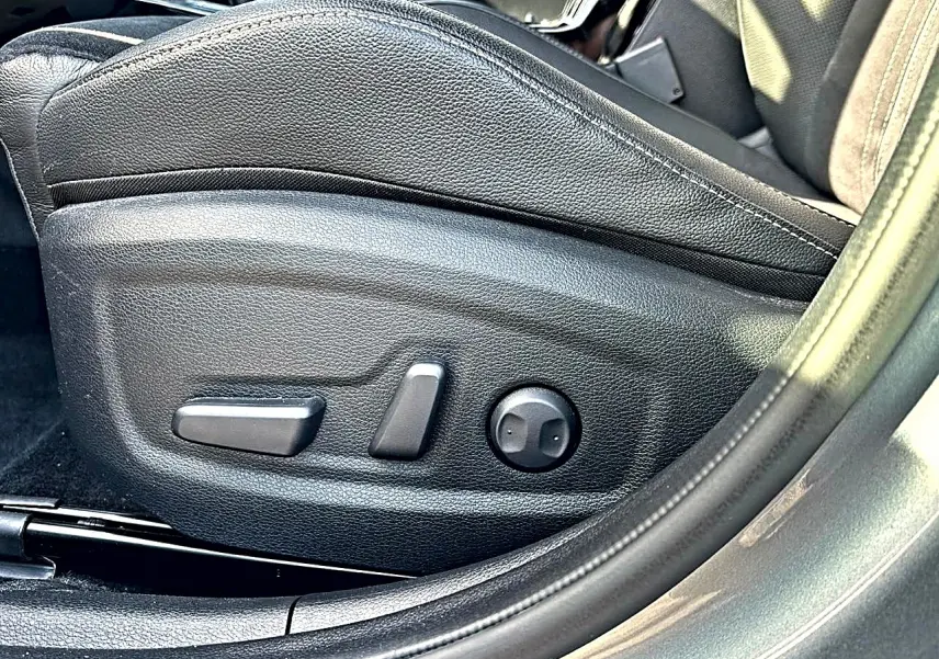 Gros plan sur les commandes de réglage électrique du siège conducteur en cuir noir du KIA Xceed gris 2024.