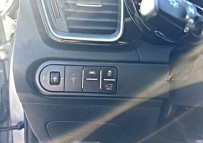 Gros plan sur les commandes d'assistance et réglages lumineux côté gauche du tableau de bord du KIA Xceed gris 2024.