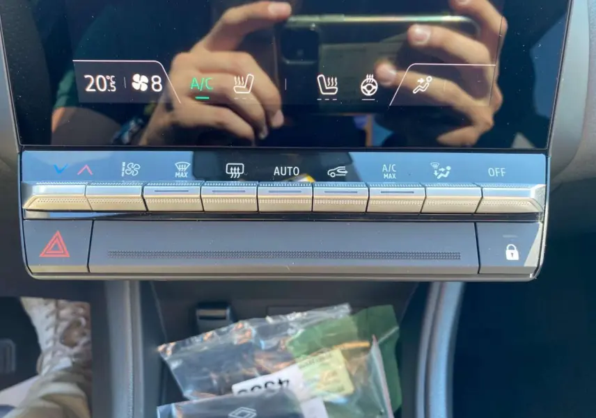 Gros plan sur la console centrale tactile du Renault Captur 2025 avec commandes climatisation et boutons argentés.