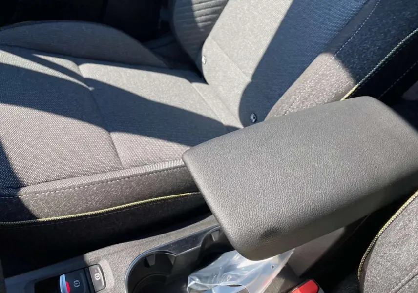 Gros plan sur l'accoudoir central et les sièges gris foncé avec surpiqûres jaunes du Renault Captur 2025.