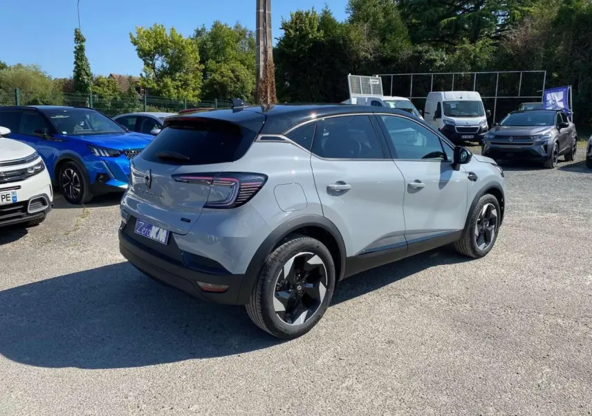 Renault Captur 2025 gris Rafale avec toit noir, vue 3/4 arrière côté droit, jantes noires distinctives.