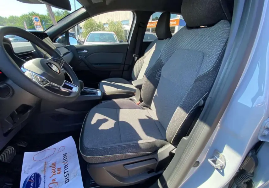 Vue intérieure côté conducteur du Renault Captur 2025 gris Rafale avec sièges tissu et volant multifonction.