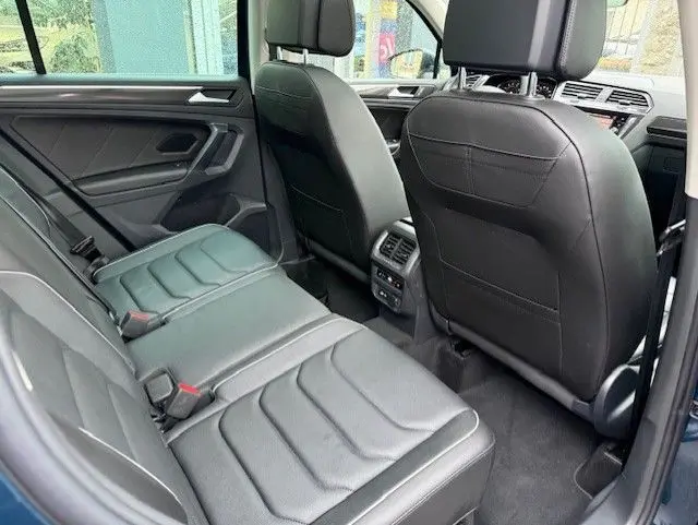Vue intérieure arrière du Volkswagen Tiguan 2022 en Night Shade Blue, sièges cuir noir avec commandes climatisation au centre.