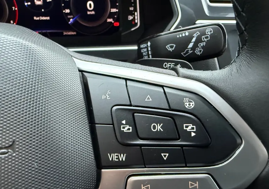 Gros plan sur les commandes multifonctions à droite du volant du Volkswagen Tiguan 2022, avec affichage numérique en arrière-plan.