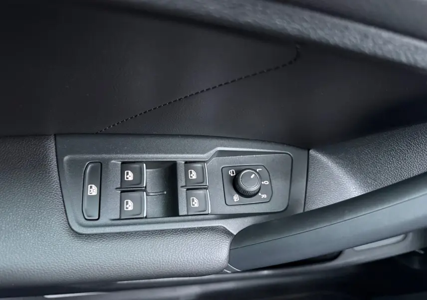 Gros plan sur les commandes des vitres et rétroviseurs côté conducteur d'un Volkswagen Tiguan bleu nuit 2022.