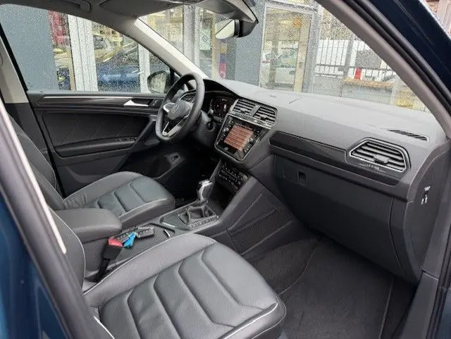 Intérieur du Volkswagen Tiguan 2022 en Night Shade Blue, vue côté conducteur montrant sièges cuir noir et tableau de bord moderne.