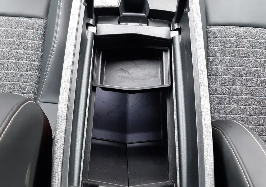 Vue plongeante sur le rangement central ouvert entre les sièges gris et noir du Peugeot 3008 III HYBRID 145 ALLURE 2025.