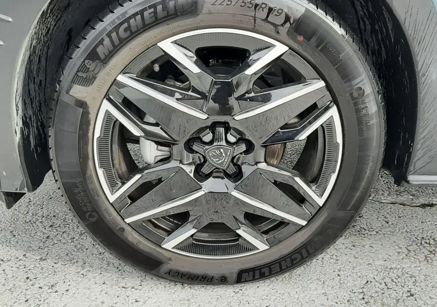 Gros plan sur la roue avant droite du Peugeot 3008 Bleu Ingaro, jante alliage noire et argentée avec logo Peugeot central.