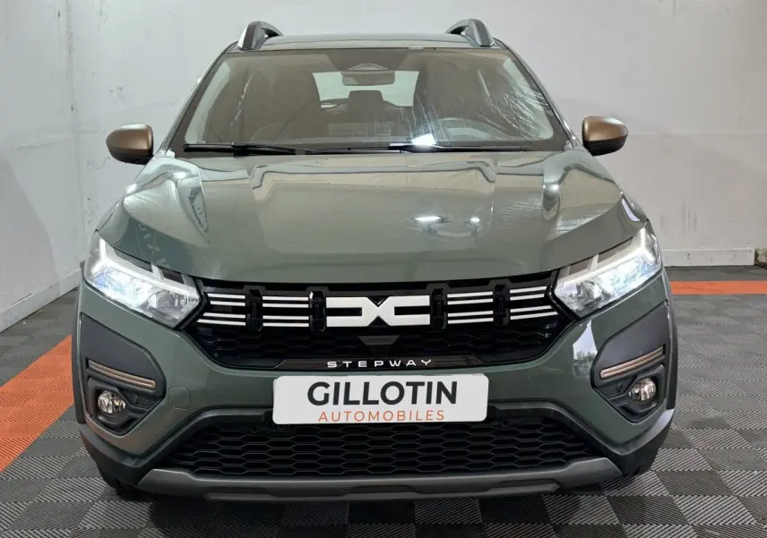 Vue frontale d'une Dacia Sandero Extreme+ TCe 110 2024 vert avec calandre noire et phares LED allumés.