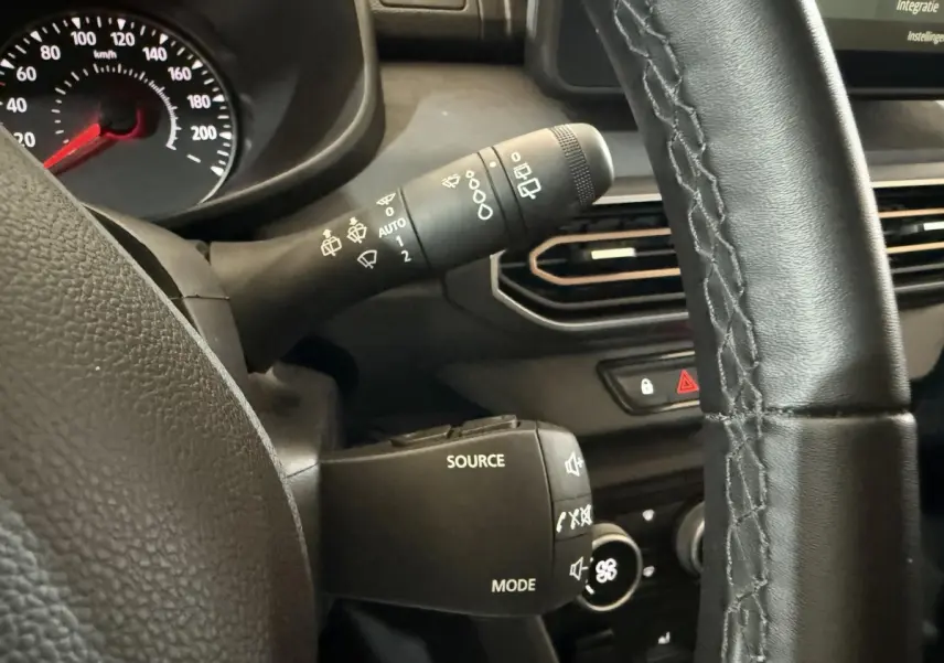 Gros plan sur le volant cuir synthétique et les commandes multifonctions du tableau de bord d'une Dacia Sandero Extreme+ verte 2024.