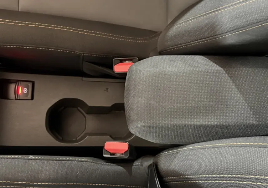 Vue rapprochée de la console centrale noire avec accoudoir tissu et boutons de frein à main électrique sur Dacia Sandero Extreme+ vert.