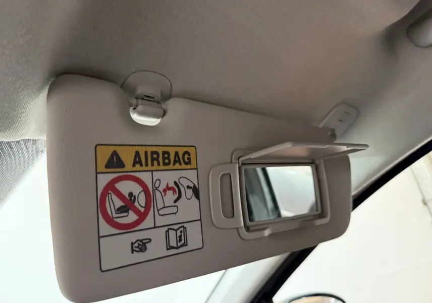 Détail du pare-soleil côté conducteur avec miroir et avertissement airbag dans un Dacia Sandero vert 2024.