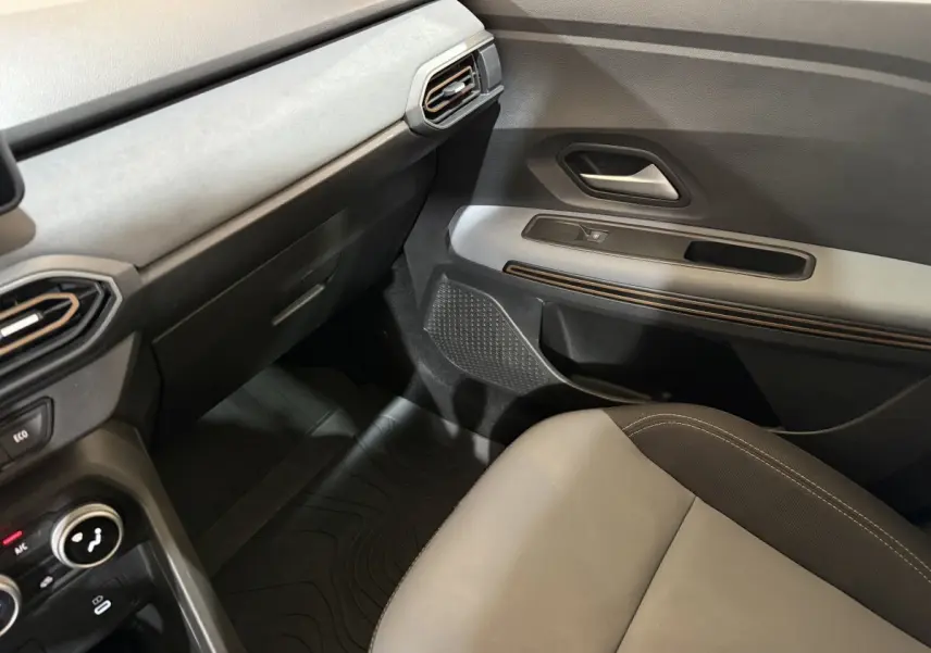 Vue intérieure côté passager avant de la Dacia Sandero Extreme+ 2024, avec siège gris et tableau de bord noir et gris.