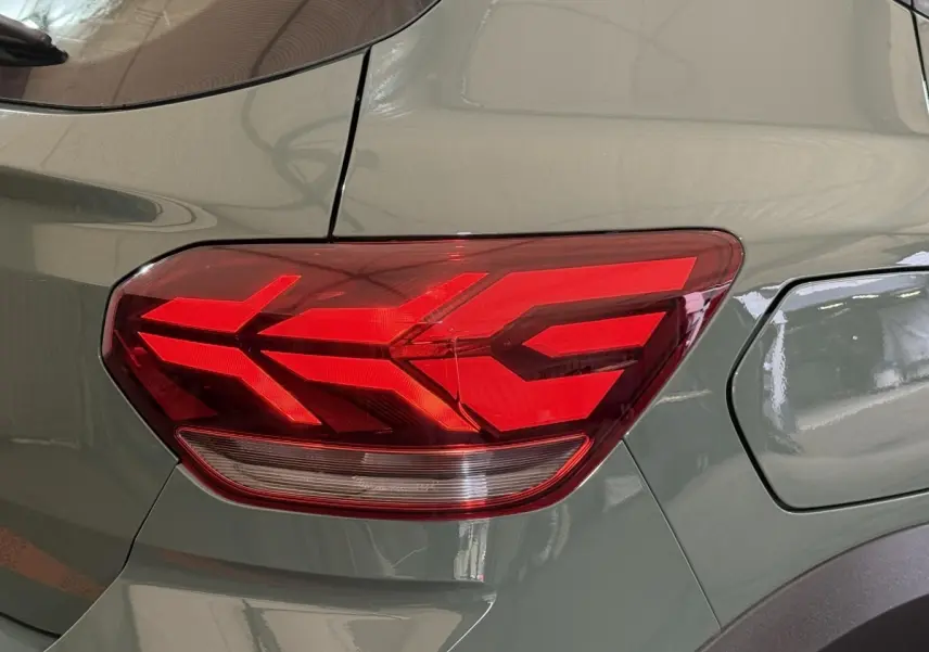 Gros plan sur le feu arrière droit rouge d’une Dacia Sandero Extreme+ vert 2024, avec la trappe à carburant visible.