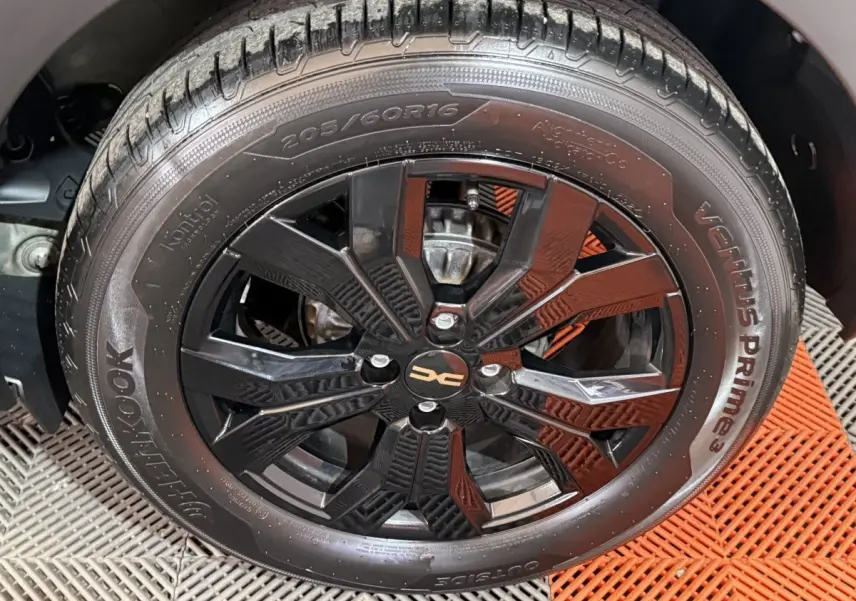 Gros plan sur la roue avant droite de la Dacia Sandero Extreme+ 2024, jante noire brillante avec logo DACIA central.