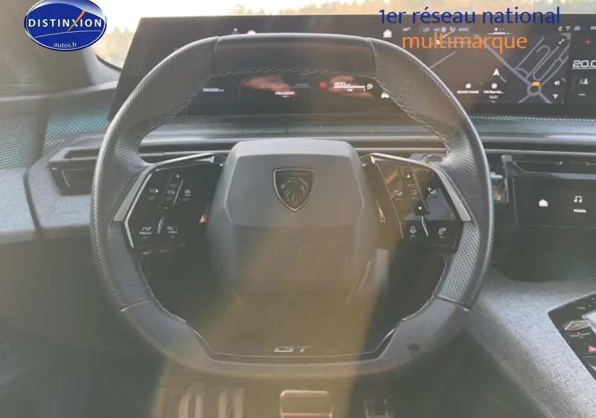 Vue rapprochée du volant cuir noir multifonction Peugeot 3008 1.2 Hybrid 145 GT avec tableau de bord numérique.