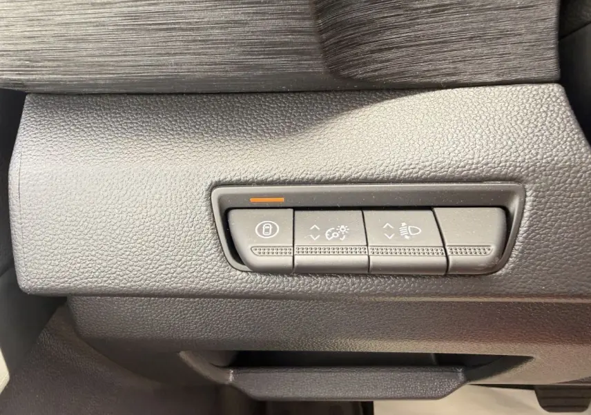 Gros plan sur les commandes de réglage des phares et du tableau de bord du Renault Trafic Fourgon blanc.