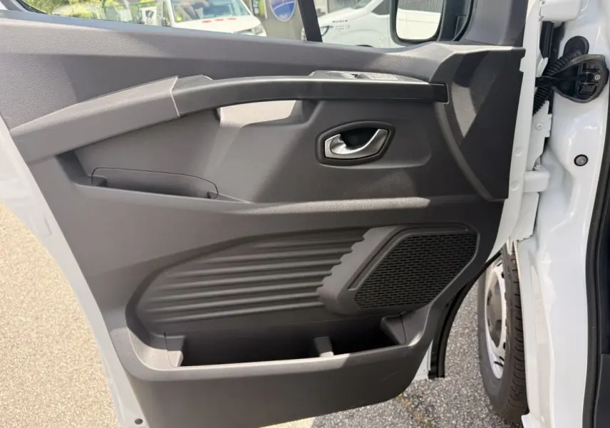 Vue rapprochée de la porte avant droite blanche du Renault Trafic Fourgon 2025, montrant la poignée et le haut-parleur intégré.