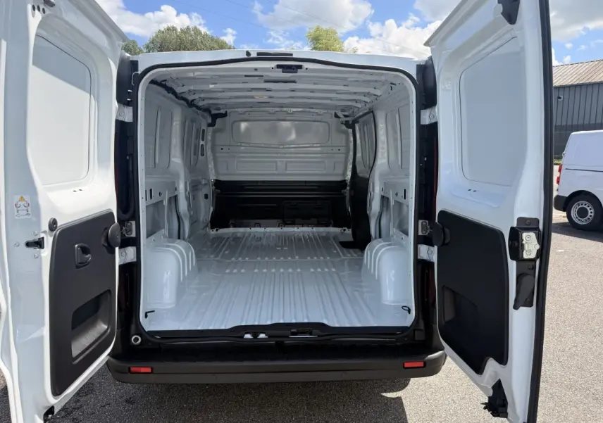 Vue arrière du Renault Trafic Fourgon blanc 2025 avec portes ouvertes montrant l'espace de chargement vide et la cloison pleine.