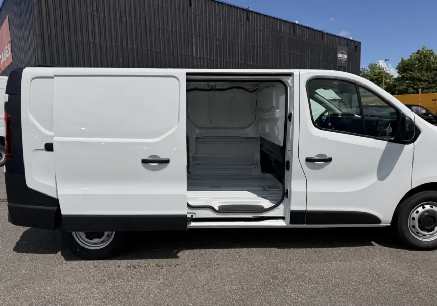 Vue latérale droite d’un Renault Trafic Fourgon blanc 2025 avec porte coulissante ouverte montrant l’espace de chargement vide.
