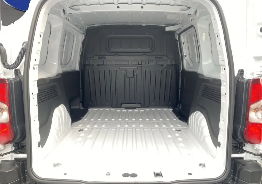 Vue arrière du coffre blanc du Peugeot Partner 2024, montrant l'espace de chargement vide avec parois noires et plancher métallique.