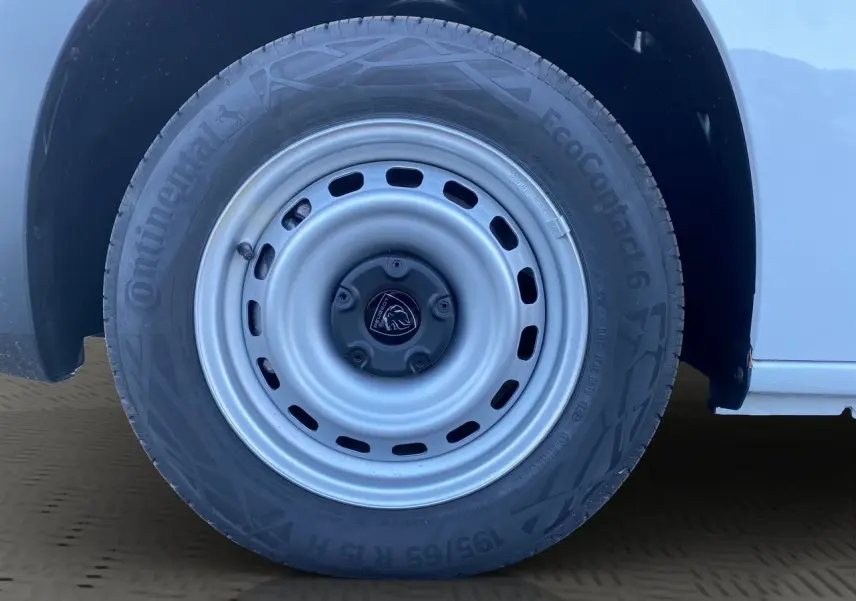 Gros plan sur la roue avant droite blanche du Peugeot Partner 2024 avec jante acier et logo lion central.