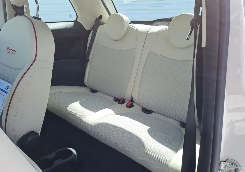 Vue intérieure côté arrière droit de la Fiat 500 blanche, sièges arrière en cuir beige clair avec appuie-têtes ronds.