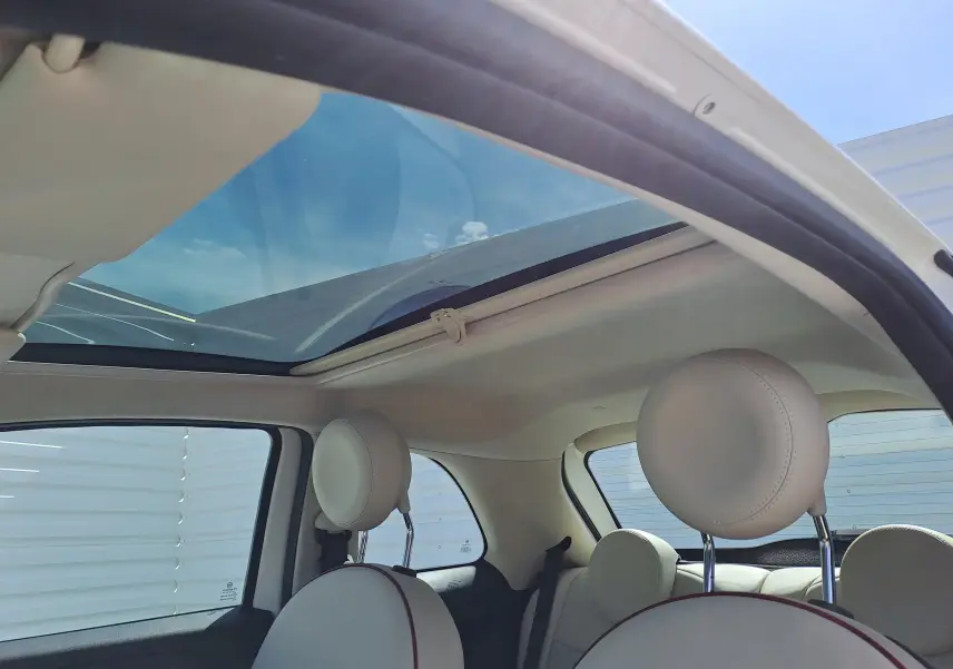 Intérieur blanc crème de la Fiat 500 1.0 Hybrid 2022 avec toit panoramique ouvrant et sièges avant arrondis.