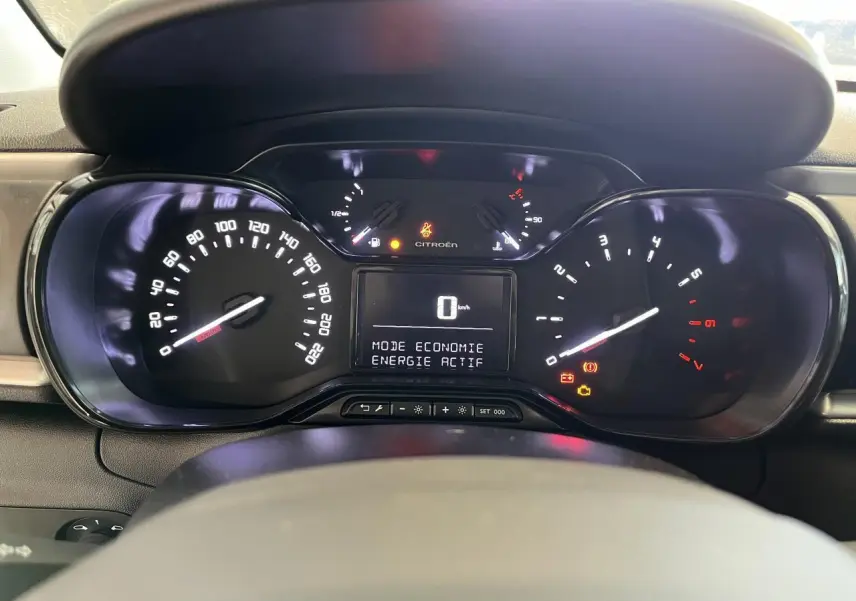 Tableau de bord de Citroën C3 2024 avec affichage numérique et compteurs analogiques éclairés au volant.