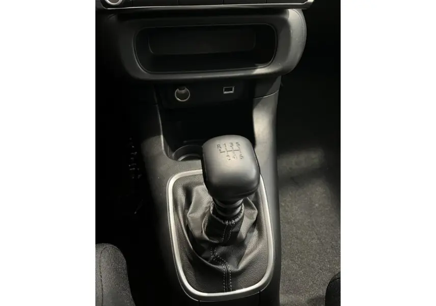 Le levier de vitesse manuel noir de la Citroën C3 2024 vu de dessus, entouré de garniture grise.